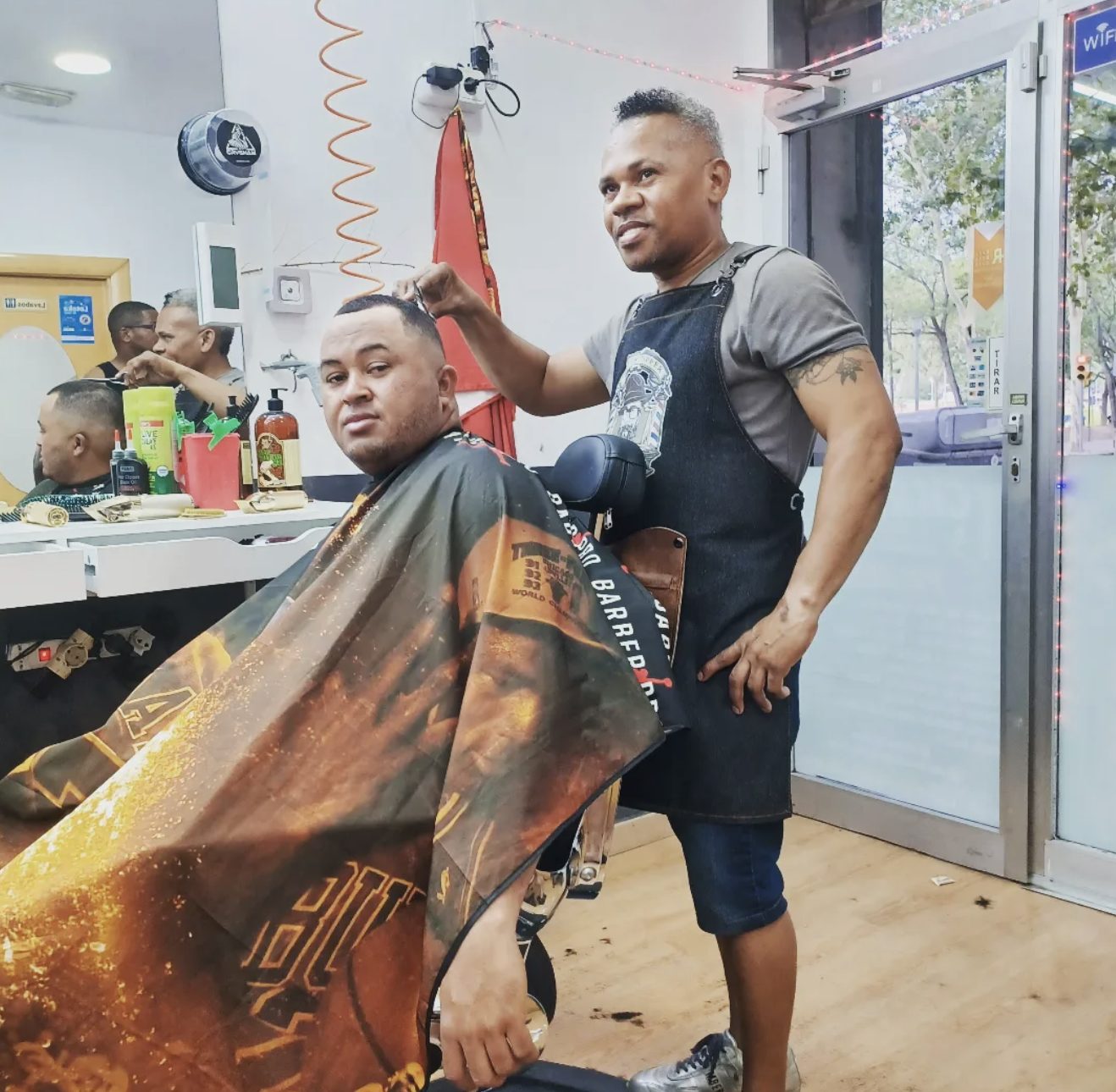 Charly cortando el pelo a un cliente en la barbería
